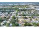 An aerial view of the neighborhood with the property indicated by a red arrow showing proximity to shopping and green spaces at 13032 Cumberland Dr, Largo, FL 33773
