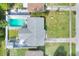 Aerial view of a backyard with a bright blue in-ground pool, a deck, a patio, and a well maintained lawn at 13032 Cumberland Dr, Largo, FL 33773