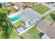 Aerial view of a backyard with a bright blue in-ground pool, a deck, a patio, and a well maintained lawn at 13032 Cumberland Dr, Largo, FL 33773