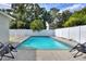 Backyard swimming pool surrounded by concrete patio, a white privacy fence, and mature landscaping at 13032 Cumberland Dr, Largo, FL 33773