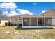 A sunny back exterior of the house with a screened-in patio and fenced-in backyard at 14385 Saltby Pl, Spring Hill, FL 34609