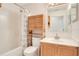 Bathroom with modern wood cabinet, a large mirror, and a combined tub and shower with wooden storage at 14385 Saltby Pl, Spring Hill, FL 34609