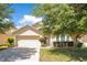 Charming single-story home with a well-maintained lawn, mature trees, and a two-car garage at 14385 Saltby Pl, Spring Hill, FL 34609