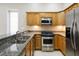 Compact kitchen boasts granite countertops, stainless steel appliances, and stylish wood cabinets for efficient cooking at 701 E 60 Hwy, Plant City, FL 33567