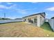Covered patio in backyard includes a grill, with a well manicured lawn and white fence at 1009 Golden Shiner Ave, Ruskin, FL 33570