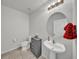 Clean half-bathroom featuring a pedestal sink, toilet, decorative mirror, and tiled flooring at 1009 Golden Shiner Ave, Ruskin, FL 33570