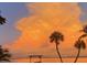Beautiful sunset with puffy clouds and a view of palm trees on the water at 1140 Boca Ciega Isle Dr, St Pete Beach, FL 33706