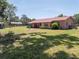 Backyard view of house with red metal roof, patio area, and mature trees at 18818 Dorman Rd, Lithia, FL 33547