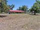 A single story home with a red metal roof and an expansive front yard with trees at 18818 Dorman Rd, Lithia, FL 33547