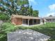 View of the home's rear brick exterior, screen porch, and large concrete patio at 115 W Lee St, Plant City, FL 33563