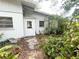Back exterior showcasing a white painted wall, entrance door, and surrounding lush landscaping at 2415 Goldenrod St, Sarasota, FL 34239