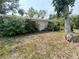 Back exterior of home showing a yard with leaves and overgrown vegetation at 2415 Goldenrod St, Sarasota, FL 34239