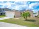 Single-story home featuring a two-car garage, green lawn, and mature palm tree at 3425 San Moise Pl, Plant City, FL 33567