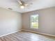 A neutral bedroom featuring wood-look floors, a ceiling fan, and a window view at 12043 Centralia Rd, Weeki Wachee, FL 34614