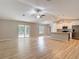 Open concept living room with wood-look flooring, ceiling fan, and a view into the adjacent kitchen at 12043 Centralia Rd, Weeki Wachee, FL 34614