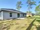 The home's spacious backyard featuring a grassy lawn and a sliding glass door to the interior at 12053 Centralia Rd, Weeki Wachee, FL 34614