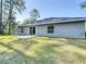 Grassy backyard featuring a sliding glass door to the home's interior and views of tall trees at 12053 Centralia Rd, Weeki Wachee, FL 34614