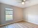 Bright bedroom features wood-look floors, neutral paint, a ceiling fan, and a large window at 12053 Centralia Rd, Weeki Wachee, FL 34614