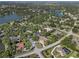 High-angle aerial shows a lakeside community with tree-lined streets, nearby houses, and lush landscaping at 7313 Crape Myrtle Way, Sarasota, FL 34241