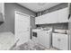 Laundry room with white cabinets, granite countertop, and modern washer and dryer at 7313 Crape Myrtle Way, Sarasota, FL 34241