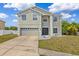 Two-story home featuring a two-car garage, neutral paint, manicured lawn, and classic architectural details at 12214 Citrus Leaf Dr, Gibsonton, FL 33534