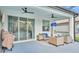 Covered patio with multiple seating areas, ceiling fans, grill, and sliding glass door access at 15706 Starling Water Dr, Lithia, FL 33547