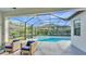 A covered outdoor patio has comfy seating next to a screened-in pool and hot tub area at 15706 Starling Water Dr, Lithia, FL 33547