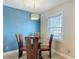A dining area with a blue accent wall, modern lighting, and a view of the window at 4778 Coquina Key Se Dr # 4778, St Petersburg, FL 33705