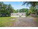 Inviting single-story home with a gravel driveway and surrounded by mature trees at 6433 Mangrove Dr, Wesley Chapel, FL 33544