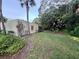 A grassy backyard with a view of the condo and surrounding trees at 135 Wild Palm Dr, Bradenton, FL 34210