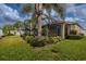 Landscaped backyard with a screened lanai, surrounded by green grass and various palm trees at 3419 Trapnell Ridge Dr, Plant City, FL 33567