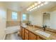 Bright bathroom featuring a double vanity with granite counters, bathtub, and tiled backsplash at 3419 Trapnell Ridge Dr, Plant City, FL 33567