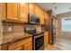 Kitchen area showcasing granite counters, brick backsplash, stainless steel appliances, and wooden cabinets at 3419 Trapnell Ridge Dr, Plant City, FL 33567