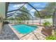Beautiful screened-in pool with outdoor seating, lush greenery, and a serene backyard setting at 11447 Adelia St, Spring Hill, FL 34608