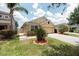 Landscaped front yard with healthy green grass, mature palms and shrubs, framed by a brick border at 12654 Belcroft Dr, Riverview, FL 33579