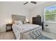 A well-lit bedroom with a tufted headboard bed, ceiling fan, and large window at 15354 Sweet Springs Bnd, Odessa, FL 33556