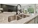 Modern kitchen island featuring granite countertops, a stainless steel sink, and a view of the open living area at 15354 Sweet Springs Bnd, Odessa, FL 33556