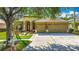 Charming home with a well-manicured lawn, mature trees, a red door, and a three-car garage at 3620 Cordgrass Dr, Valrico, FL 33596