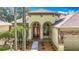 Inviting home showcasing an arched entryway, red door, stone accents, and meticulous landscaping at 3620 Cordgrass Dr, Valrico, FL 33596