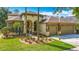 Beautiful home featuring a three-car garage, arched entryway, red door and lush landscaping at 3620 Cordgrass Dr, Valrico, FL 33596