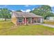Charming home featuring a covered porch with seating, a vibrant red door, and ample green space at 3715 Fortner Rd, Plant City, FL 33567