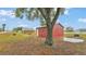 View of the red outbuilding and concrete pad near a mature tree in a spacious yard at 3715 Fortner Rd, Plant City, FL 33567
