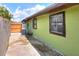 A view of the exterior and concrete patio on the side of a home with lime green paint and barred windows at 10804 N Leo St, Tampa, FL 33612