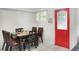 Dining area adjacent to a red door features white tile floors and a modern table set at 10804 N Leo St, Tampa, FL 33612