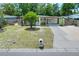 Charming single-story home with a well-manicured lawn, mature tree, and a basketball hoop on the driveway at 10804 N Leo St, Tampa, FL 33612