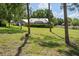 Lush backyard with mature trees offering a view of the house and a screened-in pool area at 9912 Pine Leaf Ln, Dade City, FL 33525
