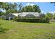 Expansive backyard featuring a screened-in pool, lush greenery, and well-maintained lawn at 9912 Pine Leaf Ln, Dade City, FL 33525