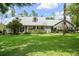 Charming curb appeal with a gray exterior, metal roof, inviting porch, and lush lawn at 9912 Pine Leaf Ln, Dade City, FL 33525