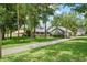 Charming home featuring mature trees, a long driveway, and well-maintained landscaping on a sunny day at 9912 Pine Leaf Ln, Dade City, FL 33525