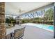 Screened lanai with a brick pillar and a serene view of the pool and lush greenery at 9912 Pine Leaf Ln, Dade City, FL 33525
